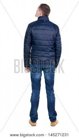 Back view of handsome man in blue windcheater looking. Standing young guy in jeans. Rear view people collection.  backside view of person.  Isolated over white background.