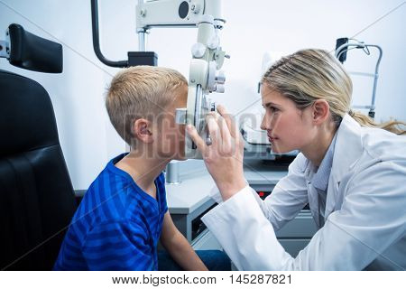 Female optometrist examining young patient on phoropter in ophthalmology clinic