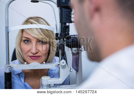 Optometrist examining female patient on slit lamp in ophthalmology clinic