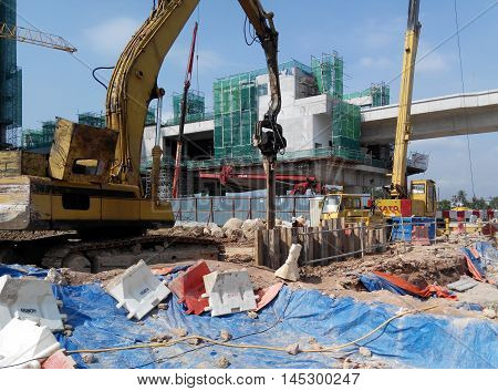 SELANGOR, MALAYSIA -MARCH 25, 2015: Sheet pile cofferdam driven machine at the construction site. The machine drove the sheet pile to the earth using vibrated hydraulic arm. Workers control.