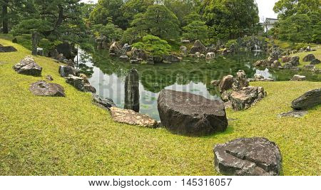 Panoramic view of Ninomaru Garden with ornamental stones in a large pond. Panorama of traditional Japanese garden during spring in Kyoto, Japan