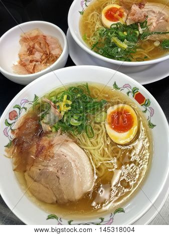 Japanese Tonkotsu ramen noodles in pork broth soup with soft boiled egg sprinkles with spring onion and dried smoked Bonito shavings
