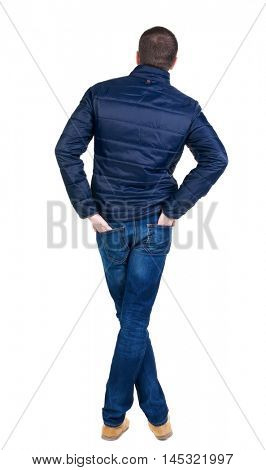 Back view of handsome man in blue windcheater looking. Standing young guy in jeans. Rear view people collection.  backside view of person.  Isolated over white background.
