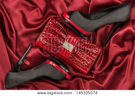 Red lacquer bag and shoes with toeless on a red crumpled fabric