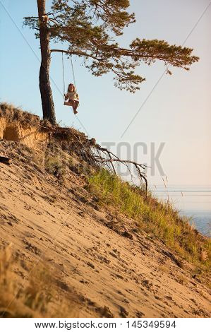 Child swinging on seesaw above a sea