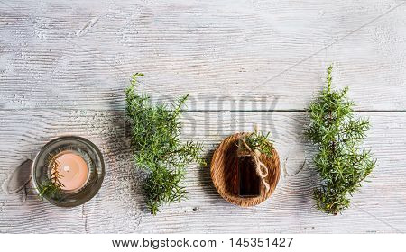 Juniper essential oil in a glass bottle on a wooden table. Used in medicine cosmetics and aromatherapy. Fresh green sprigs top view flat lay. Selective focus.