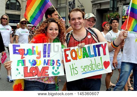 New York City - June 25, 2011: Man and woman holding rainbow signs espousing EQUALITY at the 2011 Gay Pride Parade on Fifth Avenue