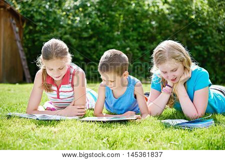 Friends Children Reading Books Outdoori On Grass