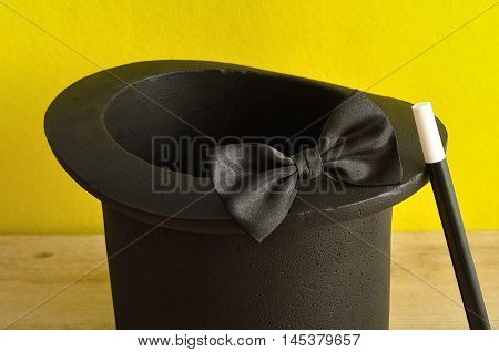A magicians hat displayed with a wand and bow tie