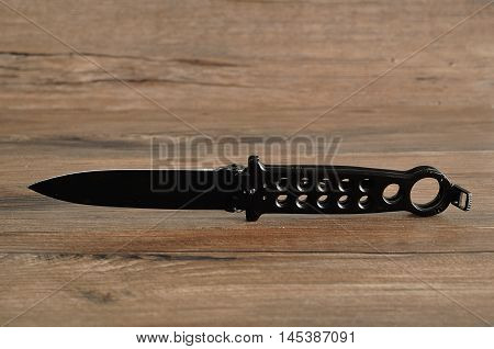 Steel butterfly knife (balisong) isolated on a wooden background