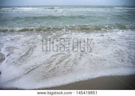 sea foam soft wave of the sea on the sand beach selective focus blurred sea