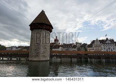 Lucerne Switzerland - May 03 2016: Evening view towards the Chapel Bridge (Kapellbruecke) together with the octagonal tall tower (Wasserturm) it is one of the Lucerne's most famous tourists attraction. Chapel Bridge joins two banks of the river Reuss. Bui