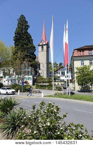 Weggis Switzerland - May 05 2016: The steeple of St. Mary's Church towering in tourist destination that is frequently visited because of the many attractions in the town itself and its surroundings. One man can be seen in a far distance.