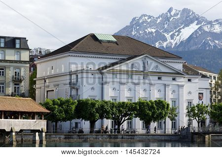 LUCERNE SWITZERLAND - MAY 09 2016: View towards the theater building that is located along the river and surrounded by other buildings. Alpine Landscape highlights the its unique character