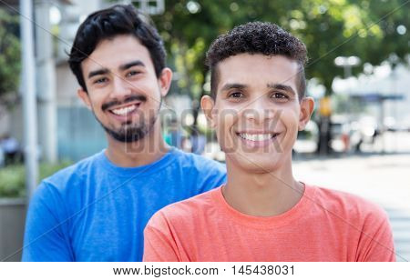 Laughing latin man with mexican friend outdoor in the city in the summer