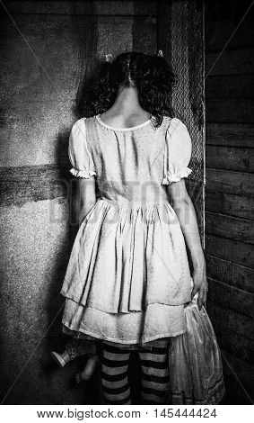 Strange girl stands turned to the wall. Rear view. Grunge texture effect