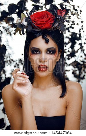 pretty brunette woman with rose jewelry, black and red, bright make up kike a vampire closeup red lips, halloween concept