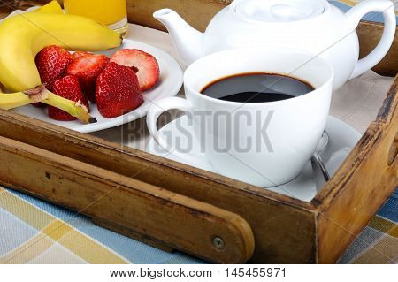 Breakfast tray with coffee orange juice and fresh fruits.