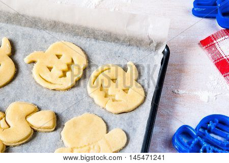 Making cookies for Halloween and Thanksgiving. Fun food for kids, a snack for a party. On a white wooden table pan with unbaked cookies