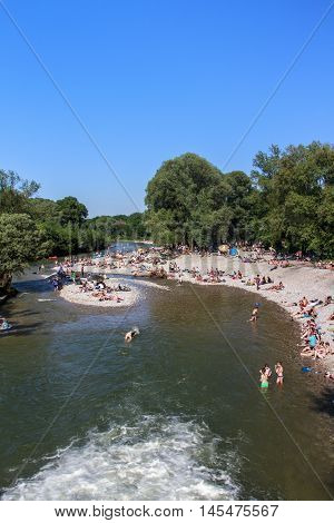 MUNICH, GERMANY - JUNE 4, 2015: The Isar river in Munich with many unidentified people on a sunny day taking a sunbath