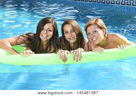 group of three happy and beautiful young girl friends having bath floating in airbed in swimming pool together having fun enjoying summer at vacation resort smiling in women holiday concept
