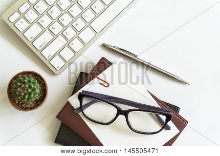 Office desk top view with smartphones, laptop eyeglasses and book / Office supplies Blank and pen notebook and earphones on white background