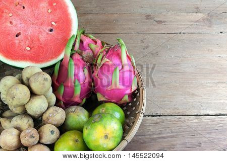 Asian fresh fruits. Langsat and watermelon and Orange and Dragon fruit in bamboo basket.