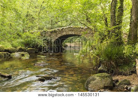 A riverside image of Hisley Bridge an old packhorse bridge over the river Bovey shot at Dartmoor Devon England UK