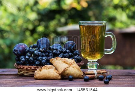 Warming tea with cinnamon and cakes with apples. Chokeberry and plums. Autumn harvest. Autumn concept. Seasonal concept. Homemade food. Tea party outdoors.