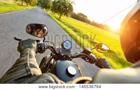 Motorcycle driver riding on motorway in beautiful sunset light. Shot from pillion driver view