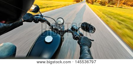 Motorcycle driver riding on motorway in beautiful sunset light. Shot from pillion driver view
