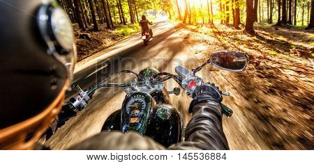 Motorcycle drivers riding on motorway in beautiful sunset light. Shot from pillion driver view