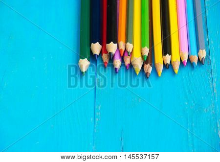 Colored pencils on a blue wooden background. Copy space