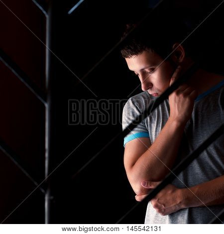 sad man behind bars thinking about something