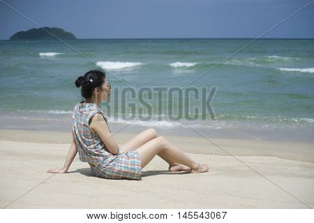 Young Asian Woman Take A Rest On The Beach With Blurred Sea Background,selective Focus,natural Color