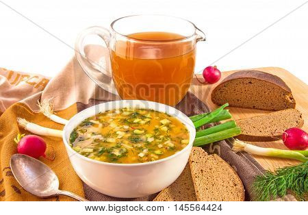 Traditional russian summer cold kvass soup okroshka in a white ceramic bowl jug with kvass (kvas) radish green onion and black rye bread on wooden cutting board. Healthy food concept. White background. Horizontal.