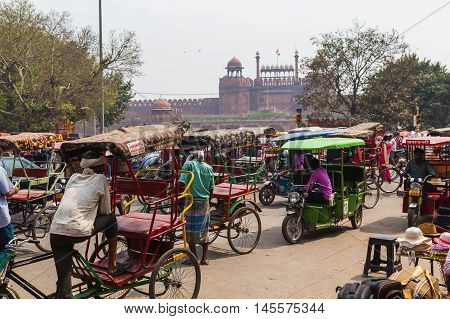 DELHI INDIA - 19TH MARCH 2016: Large amounts of Tuk Tuk Rickshaws in central Delhi during the day. The Red Fort can be seen in the distance.