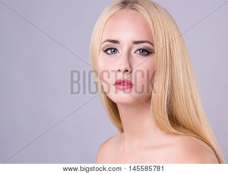 Beautiful blonde model woman face with blue eyes and perfect make-up. Portrait of beauty young blond girl with pink lips. Female face with clear skin close-up. Skincare