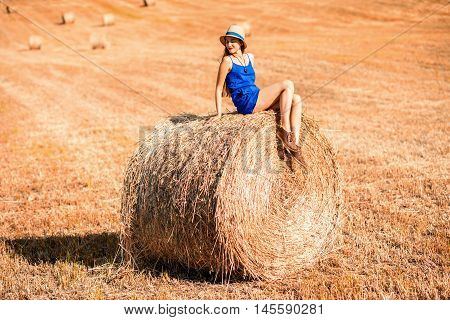 Young woman in blue dress enjoying nature on the hayfield in Tuscany in Italy