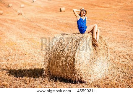 Young woman in blue dress enjoying nature on the hayfield in Tuscany in Italy