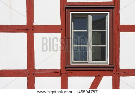 The close-up of the beam construction of a half-timbered house with window.