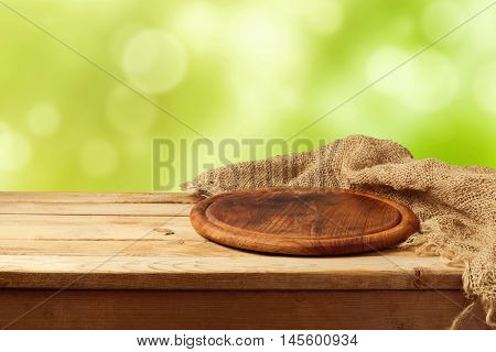 Round ooden board with sackcloth over green bokeh background