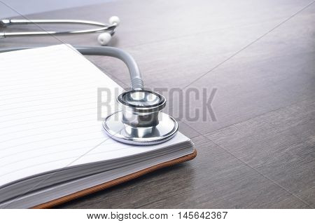 Stethscope on top of notebook with wooden background