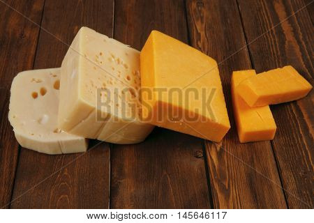 various types of fresh raw aged delicatessen cheese on wooden table cheddar edam swiss