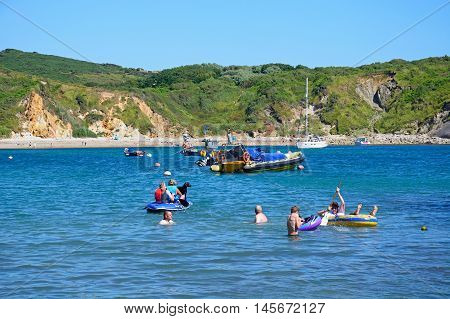 LULWORTH COVE, UNITED KINGDOM - JULY 19, 2016 - Holidaymakers relaxing in the sea with the beach to the rear Lulworth Cove Dorset England UK Western Europe, July 19, 2016.