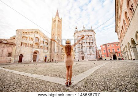 Young female tourist standing back on the central square with cathedral and famous leaning tower on the background in Parma town. Having great vacations in Parma
