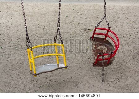 Broken swing hanging on the playground. Danger