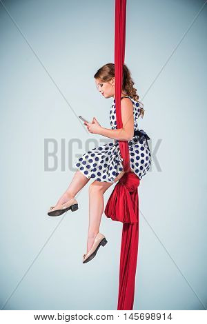 Graceful gymnast sitting on red fabrics in dress and shoes and laptop