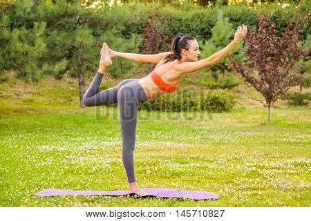Young Woman Practicing Yoga In The Park.