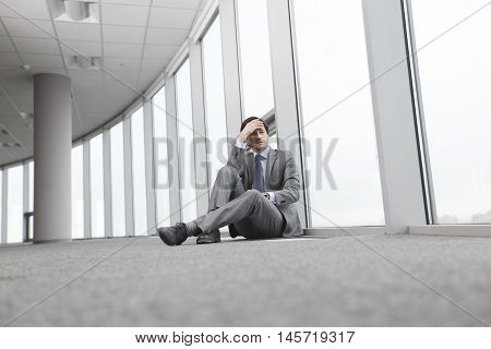 Businessman sitting on floor in office near window